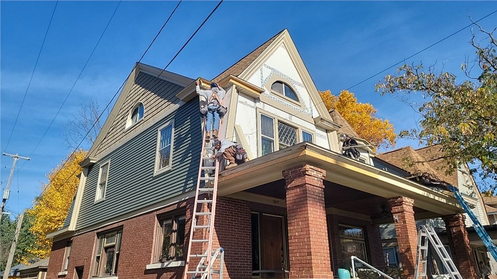 Contractors installing new siding on Grand Rapids home during exterior renovation.