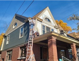 Contractors installing new siding on Grand Rapids home during exterior renovation.
