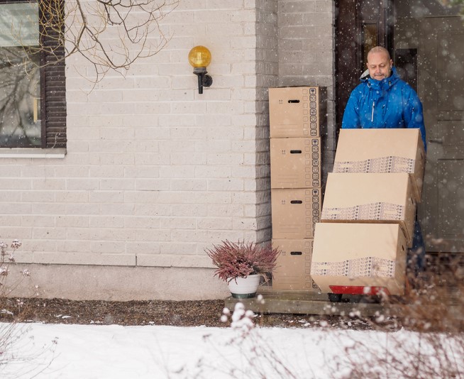 Person with boxes stacked on a dolly in the snow