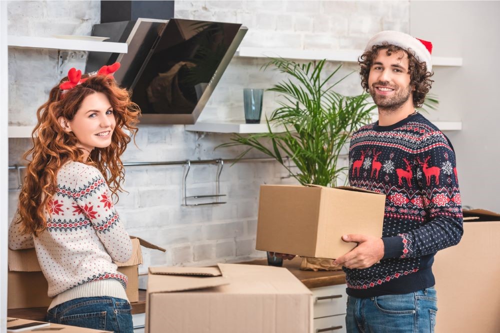 Two people in holiday sweaters packing boxes