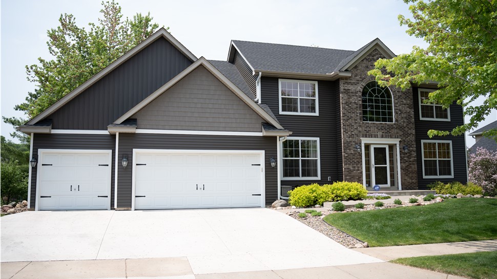 Two story home with dark brown siding and dark gray roof and different kinds of siding