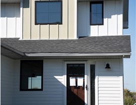 close up of black framed windows and white and tan wood grain siding