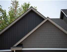close up of two gables above two garage stalls, one one side is board and batten siding and one is shakes