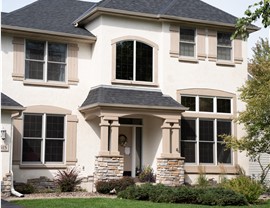 close up of cream colored stucco home with black roof