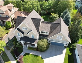 drone image of yellow tan home and dark colored roof