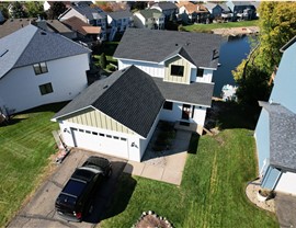 drone image of white and tan home with dark gray roof