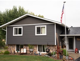 close up of home with dark gray vinyl lap siding and board and batten dark brown siding