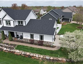 drone image of modern farmhouse, boulder wall in front yard and white flowering tree to the right of the home