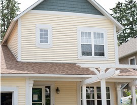 close up of yellow home with green gable and orange tan roof