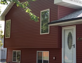 red one story home with vinyl siding and black gutters