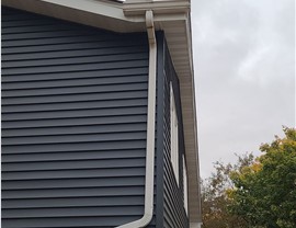 side of a blue house with white gutters