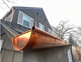 close up of copper gutters on home with wood shake siding