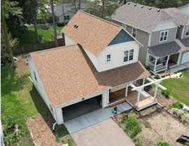 drone image of yellow home with green gable and orange tan roof