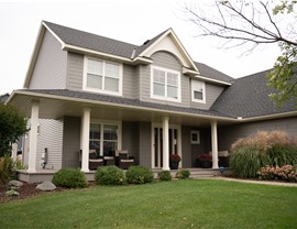tan gray two story home with large wrap around porch