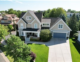 drone image of yellow tan two story home with blue garage door