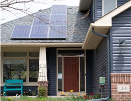 Close up of blue home's red front door and solar panels on the roof