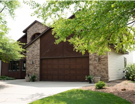 Brown one story home with brick, dark wood siding, and light brown vinyl siding