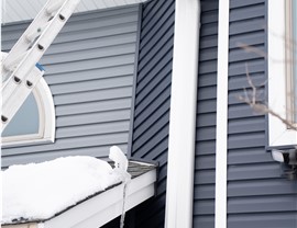 two portions of vinyl siding meet on a corner of a home, dark blue and gray.