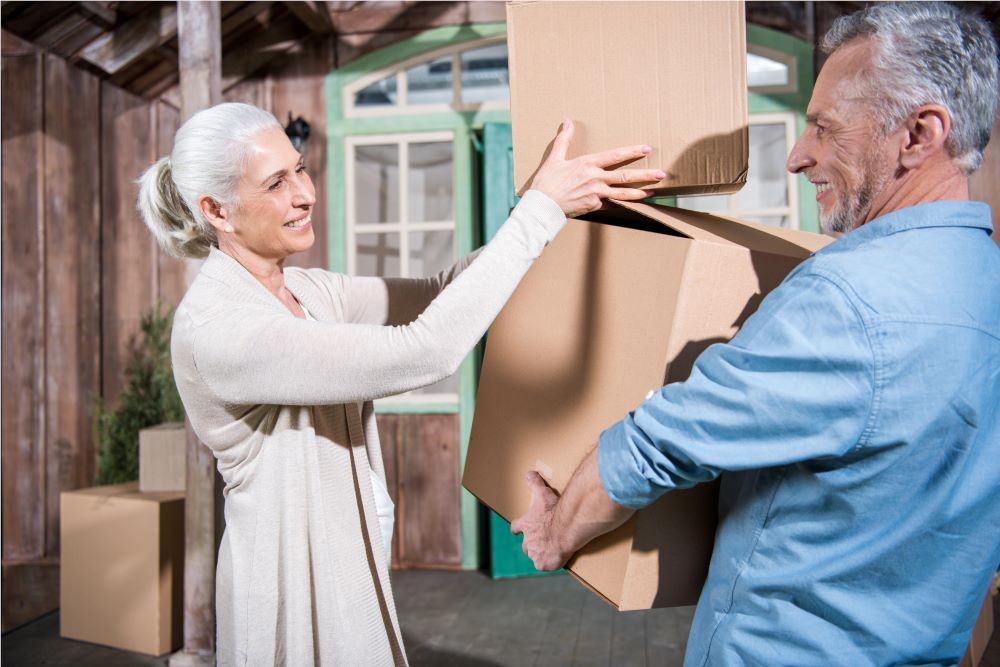 Smiling couple with moving boxes in front of a house