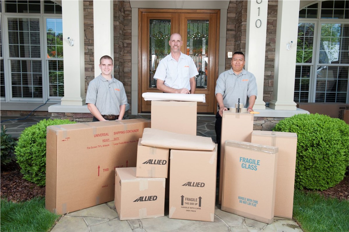 Movers in front of house with carefully packed boxes