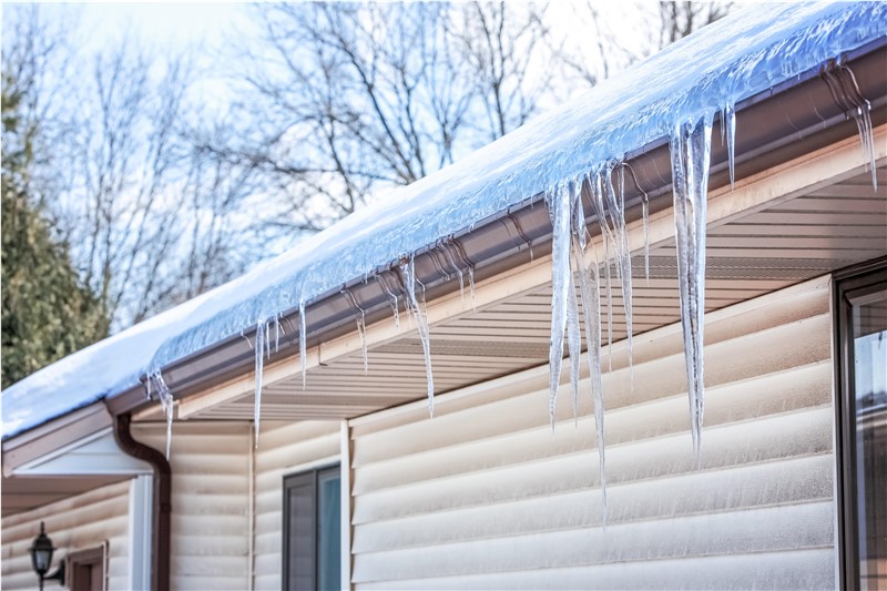 Gutters frozen solid with an ice dam blocking any melting water from flowing out of the gutters.