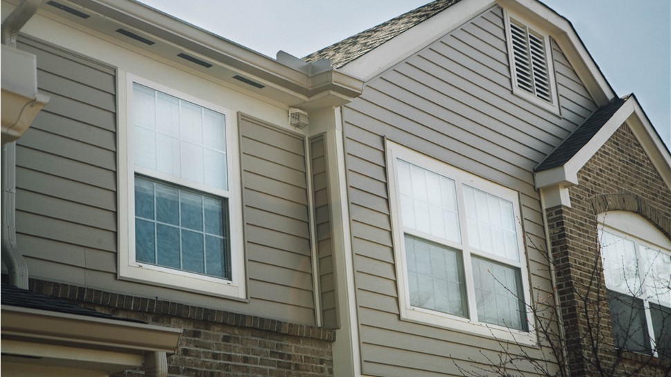 Windows with white trim on a home with tan vinyl siding