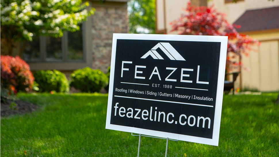 A yard sign with the words 'Feazel' is displayed on a front lawn