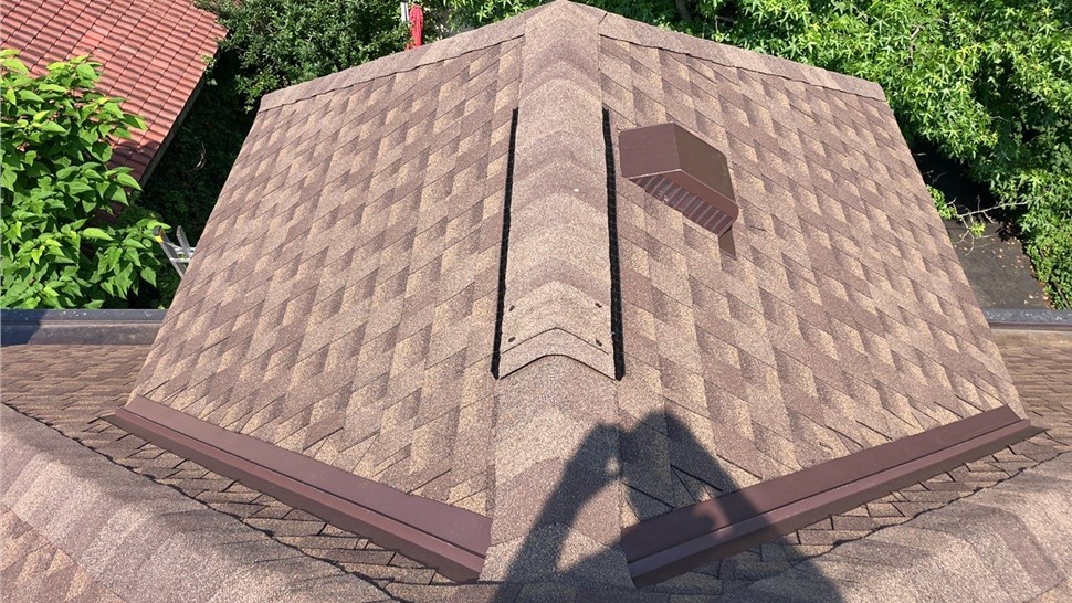 A newly installed Barkwood Timberline HDZ shingle roof in Mount Lookout, OH, featuring brown shingles, ridge vents, and attic ventilation under a sunny sky.