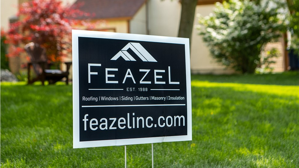 A yard sign with the words 'Feazel' is displayed on a front lawn