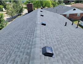 Close-up of a newly installed roof in Middletown, Ohio, featuring Charcoal Timberline HDZ shingles with ridge vents and attic ventilation under a bright blue sky.