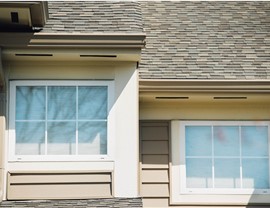 Two new windows with white trim on the side of a home