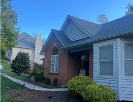 A home in Cleves, Ohio, with a newly installed roof featuring Pewter Gray Timberline HDZ shingles, surrounded by green grass, shrubs, and trees, enhancing its curb appeal.