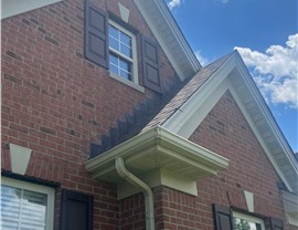 Close-up view of a brick house in Liberty Township, Ohio, with a newly replaced roof using Barkwood GAF Timberline HDZ shingles, showcasing the home's architectural details under a bright blue sky.