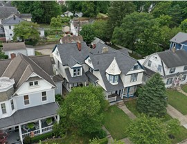 Queen Anne-style home in Newark, Ohio, featuring white siding with blue accents and a Pewter Gray shingled roof. The newly installed roof includes a ridge vent for proper ventilation, enhancing protection and airflow.