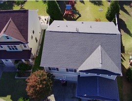 Aerial view of a Cary, NC home with a newly installed Pewter Gray shingle roof, featuring a clean finish and surrounded by well-kept homes, manicured lawns, and a backyard playset.