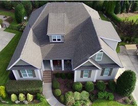 Aerial view of a home in Wake Forest, NC, with a newly installed Weathered Wood Timberline HDZ roof. The architectural shingles complement the house's design, surrounded by lush landscaping and a curved walkway.