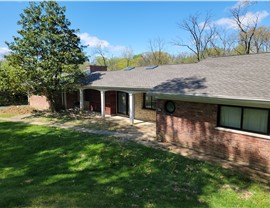 Brick ranch-style home in Blue Ash, Ohio, showcasing a new roof with Weathered Wood Timberline HDZ shingles from GAF, surrounded by greenery and a manicured lawn.