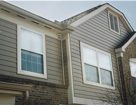 Windows with white trim on a home with tan vinyl siding