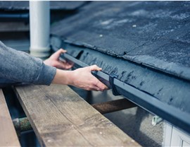 A man installs new gutters