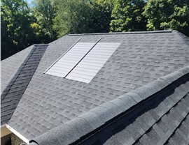 Aerial view of a Timberline HDZ shingle roof replacement combined with GAF solar shingles, capturing sunlight to generate solar energy.