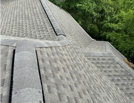 A newly installed roof in Milford, OH, featuring Weathered Wood Timberline HDZ shingles. The roof has clean lines and ridge caps, with green trees visible in the background, showcasing the natural look and durability of the shingles.