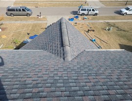 Newly installed Williamsburg Slate GAF Timberline HDZ shingles on a residential roof, with tools, ladders, and work vehicles visible on the ground as part of an active roofing project.