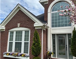 Front of a red brick home in Mason, OH featuring new Charcoal Timberline HDZ shingles, white trim, and colorful flower boxes.