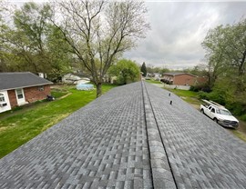 A roof replacement in Middletown, Ohio, showcasing Pewter Gray Timberline HDZ shingles with a scenic view of nearby homes, trees, and a cloudy sky in the background.