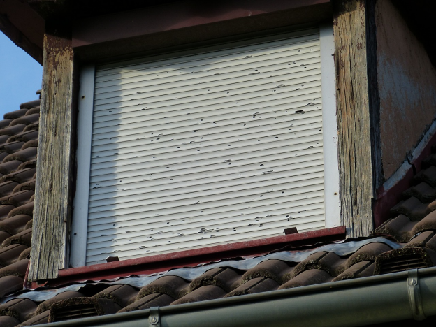 a closed shutter window on roof of a house 