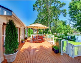 Wood deck with patio umbrella and dining set surrounded by trees