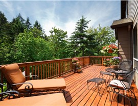 Wood deck with lounge chairs and railing overlooking wooded backyard
