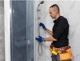Bathroom contractor completing professional shower installation with marble-look wall panels