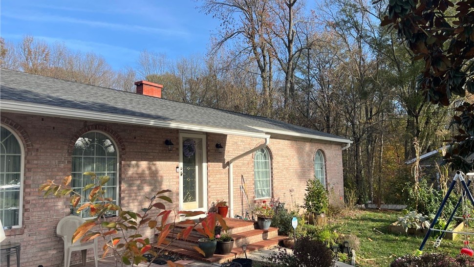 Brick single-story home in Alexandria, VA, featuring a paver patio and a front yard garden. The light red brick exterior is complemented by a new roof with Pewter Gray Timberline HDZ shingles.