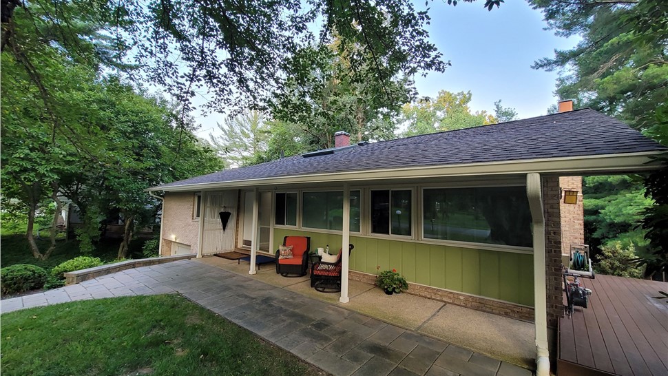 Mid-century house in Bethesda, MD with a new Timberline HDZ shingle roof, large windows, and a covered patio area nestled in a green backyard.